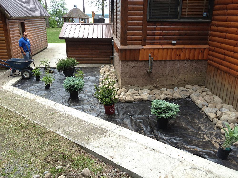 A man is pushing a wheelbarrow in front of a house.
