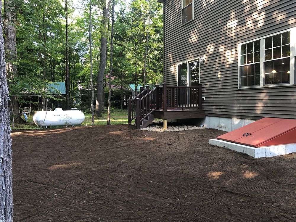 A house with a deck and a propane tank in the backyard.