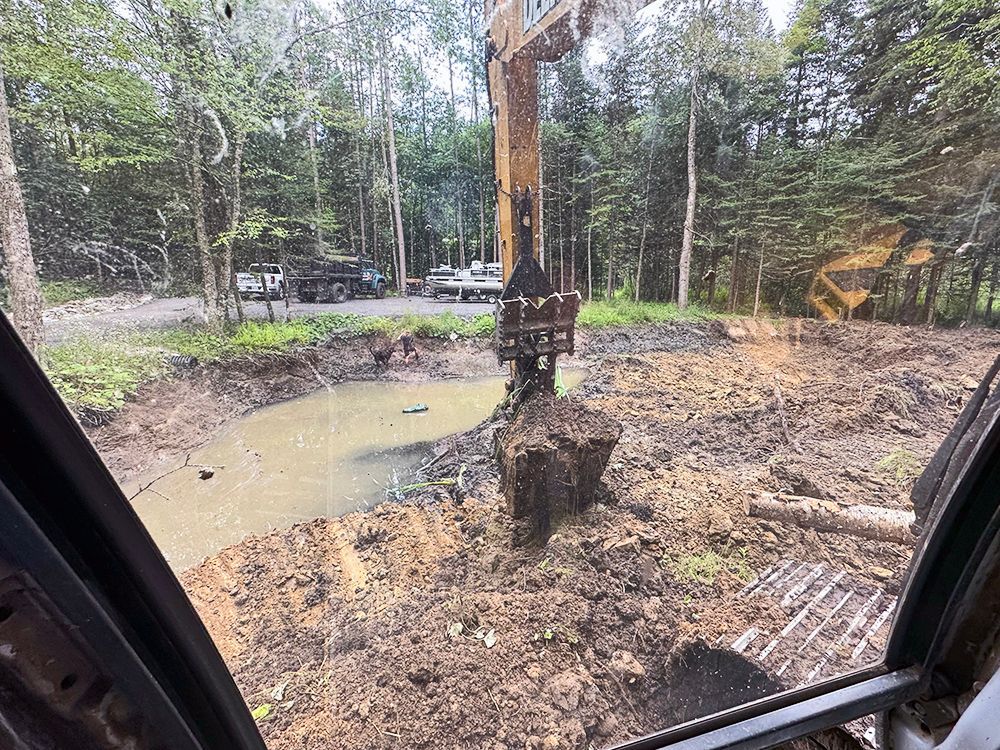 A large excavator is digging a hole in a muddy field.
