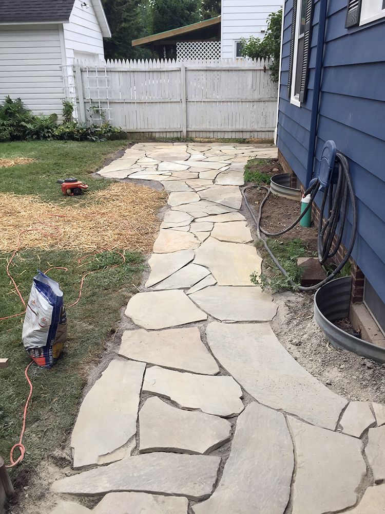 A stone walkway is being built in the backyard of a house.