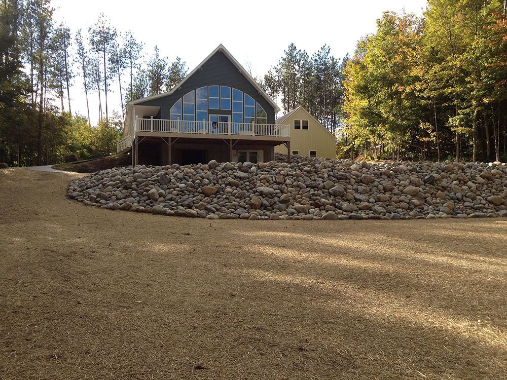 A large house with a lot of windows is surrounded by trees and gravel.