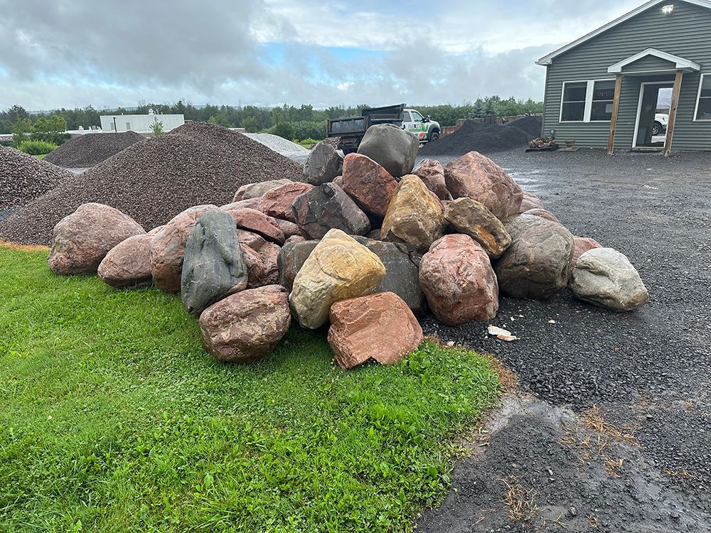 A pile of rocks is sitting in the grass in front of a house.