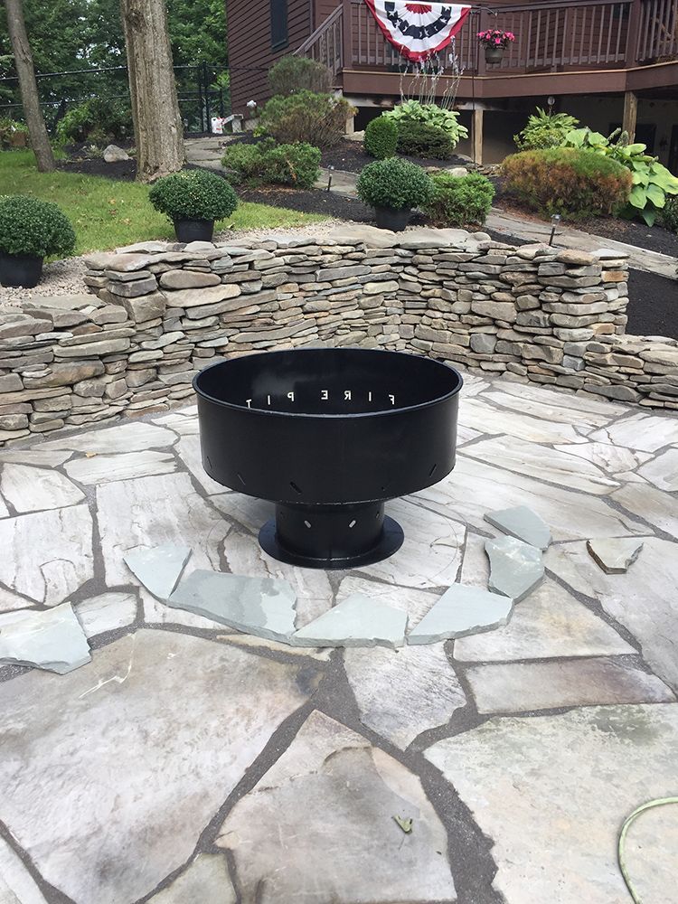 A black fire pit is sitting on top of a stone patio.