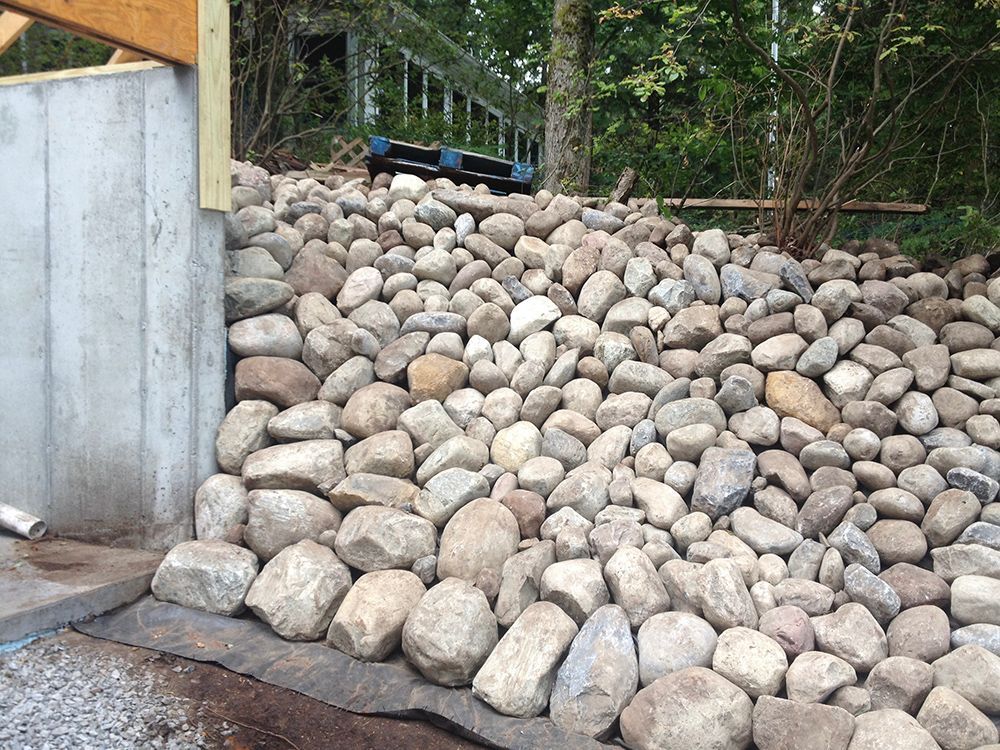A pile of rocks is sitting next to a concrete wall.