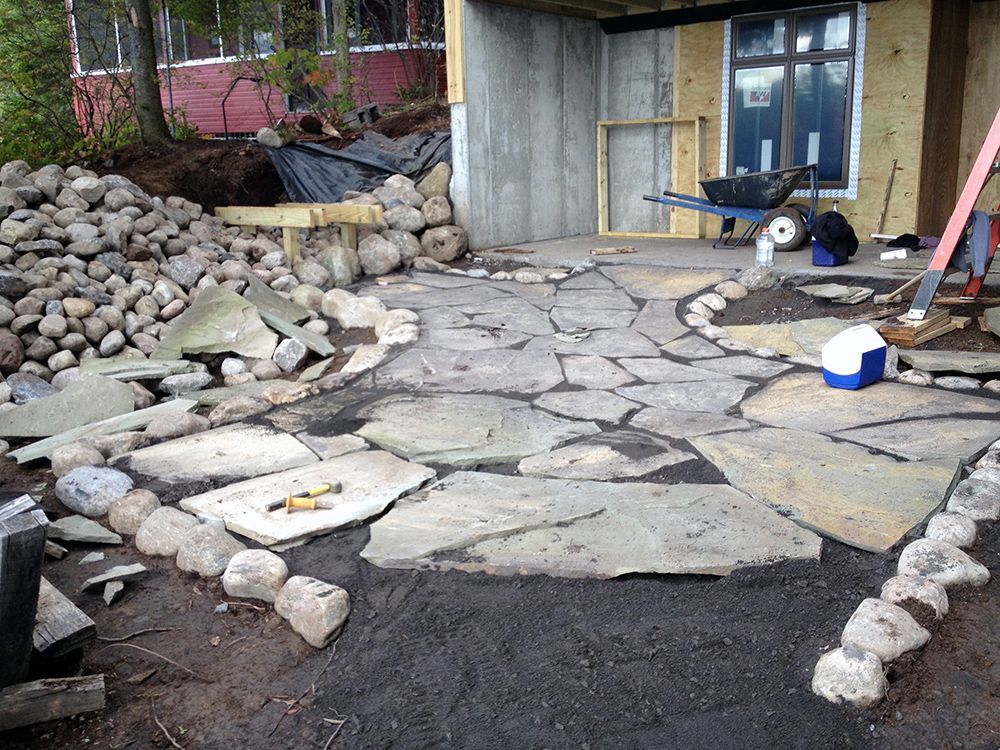 A stone walkway is being built in front of a house.