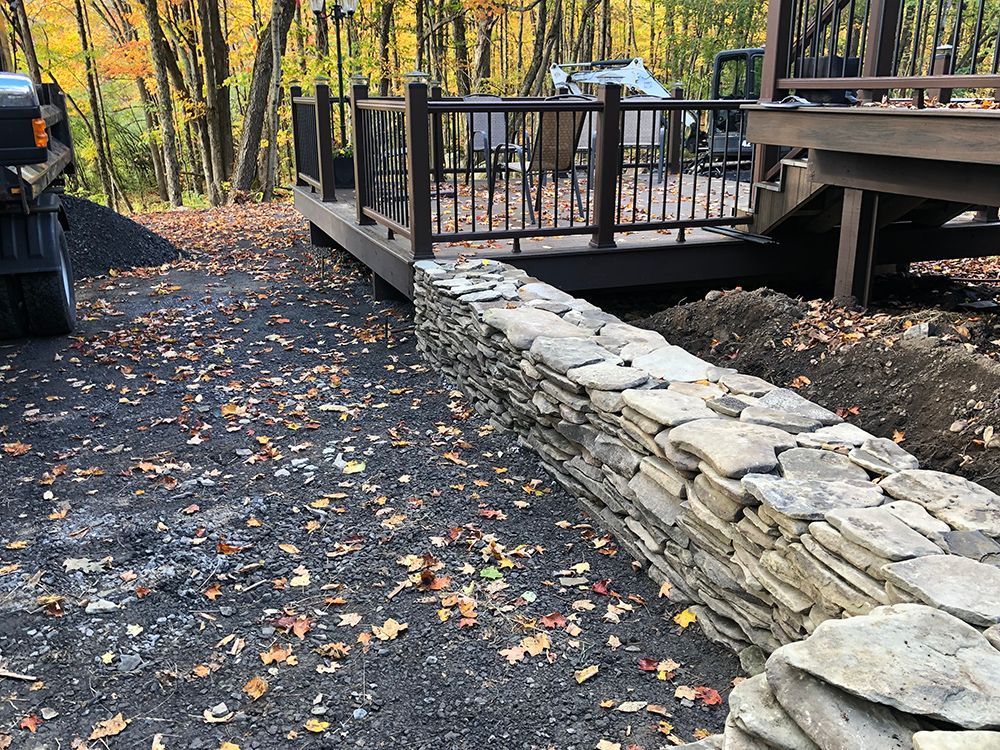 A stone wall is being built next to a wooden deck.
