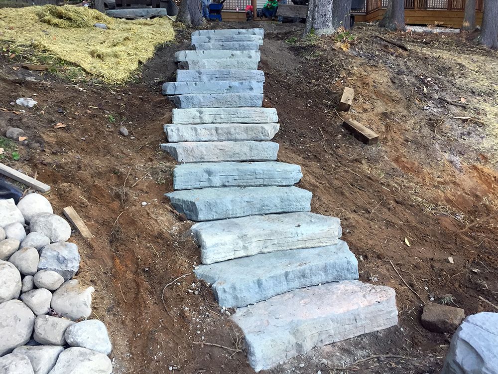 A row of stone steps going up a dirt hill.