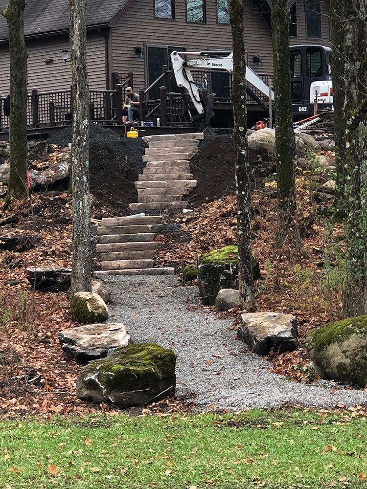 A house with stairs leading up to it is surrounded by trees and rocks.