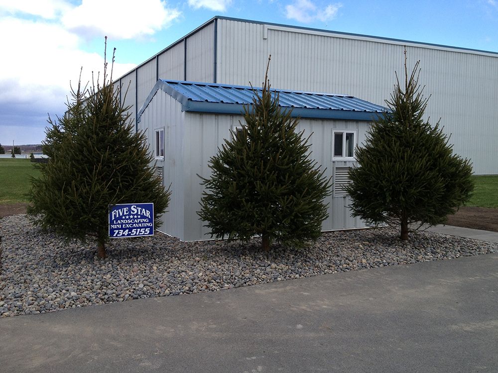 A white building with a blue roof and trees in front of it