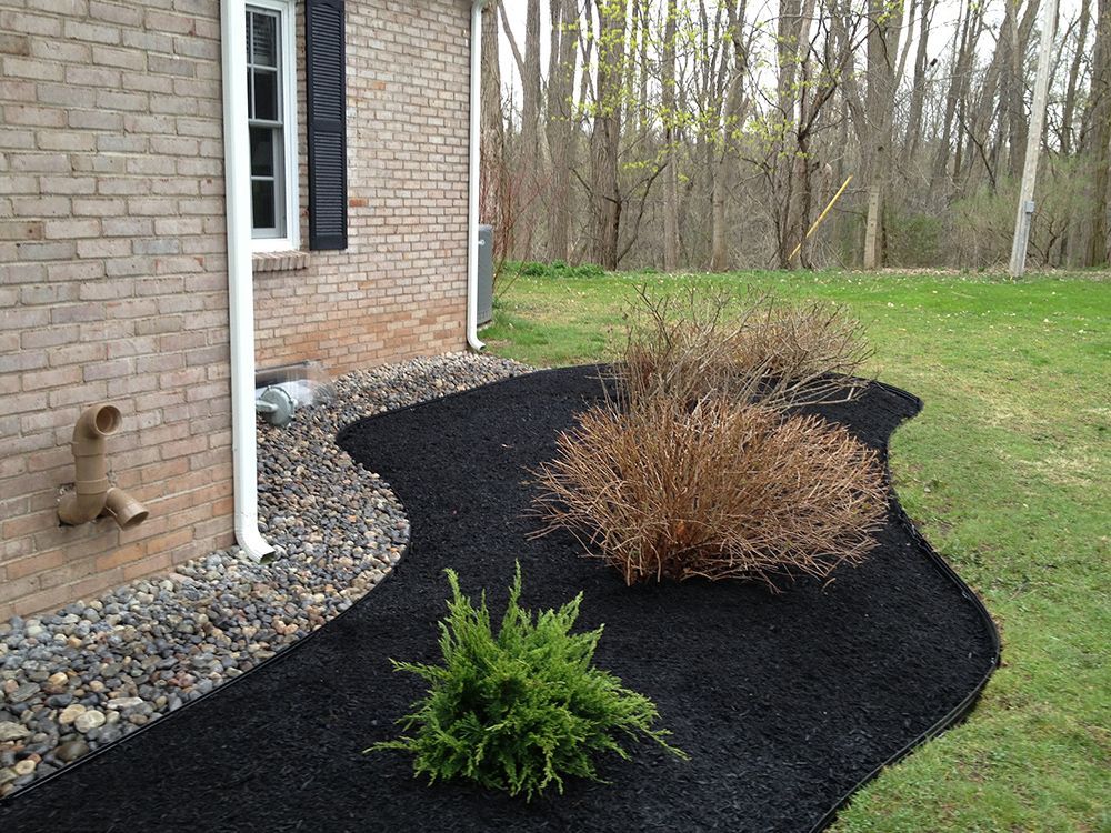 A brick house with a black mulch bed in front of it