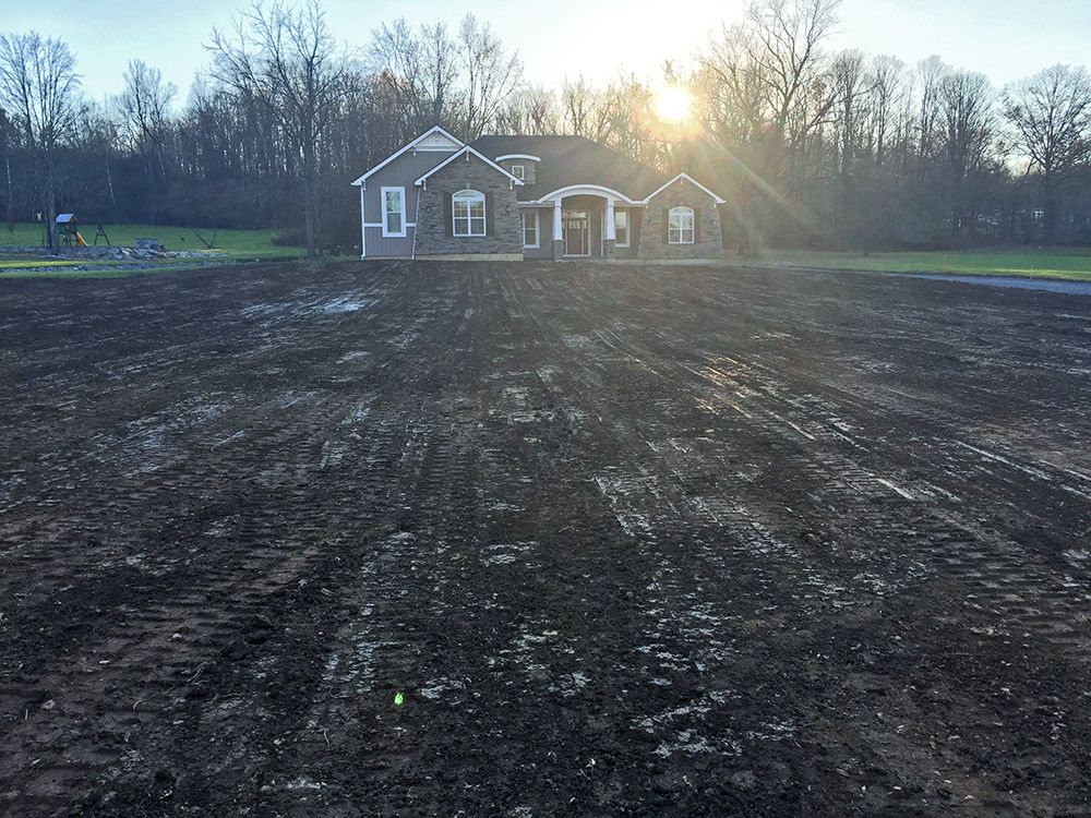 A house is sitting in the middle of a dirt field.