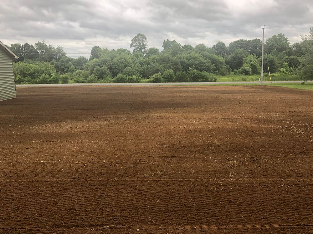 A large dirt field with a white building in the background.