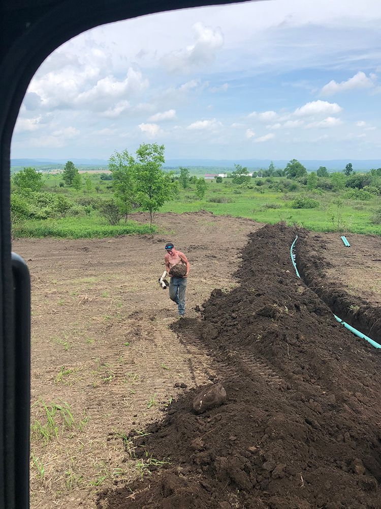 A man is standing in the middle of a dirt field.