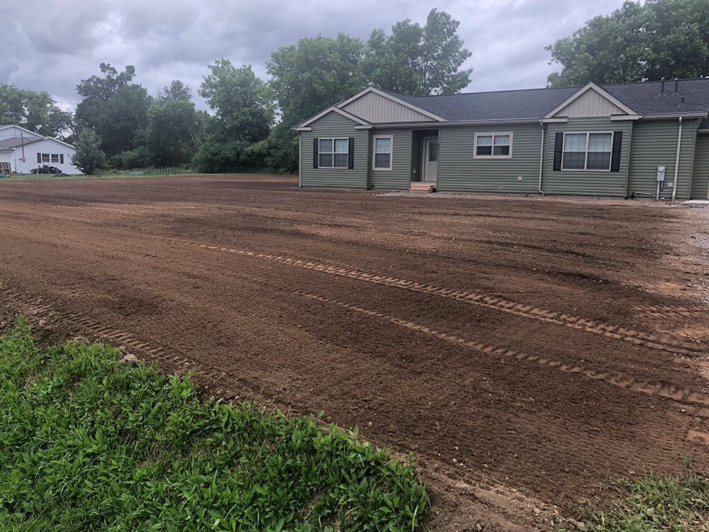A house is sitting in the middle of a dirt field.