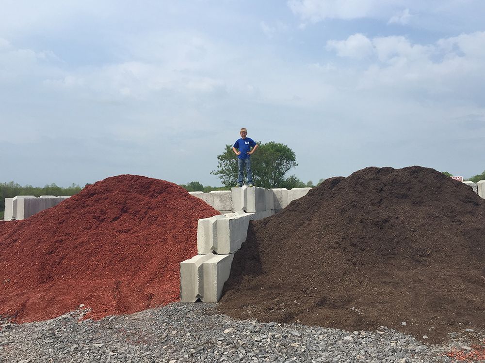 A man is standing on top of a pile of mulch.