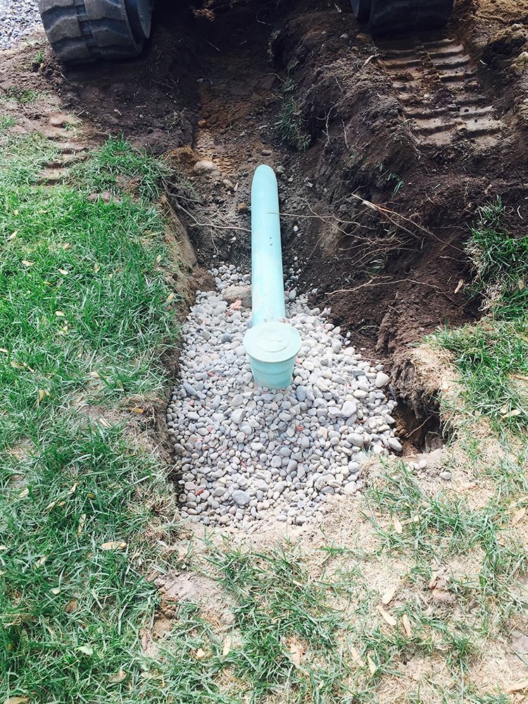 A blue pipe is sitting in the dirt next to a gravel area.