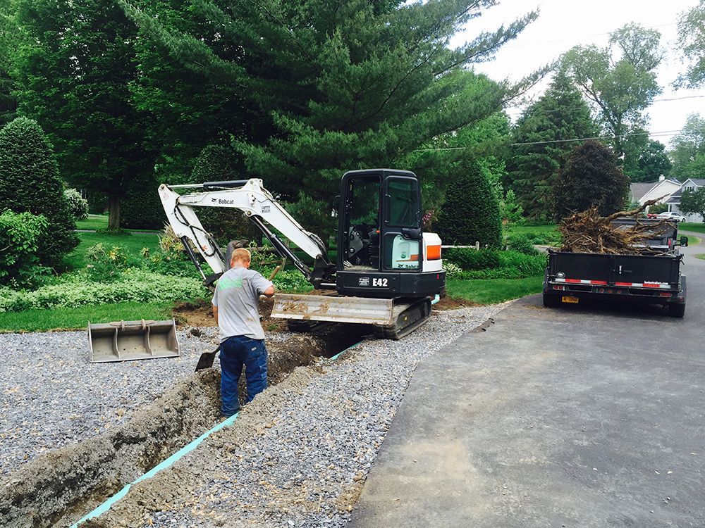 A man is standing in front of a bobcat excavator