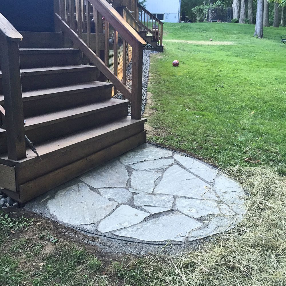 A wooden deck with stairs and a stone walkway