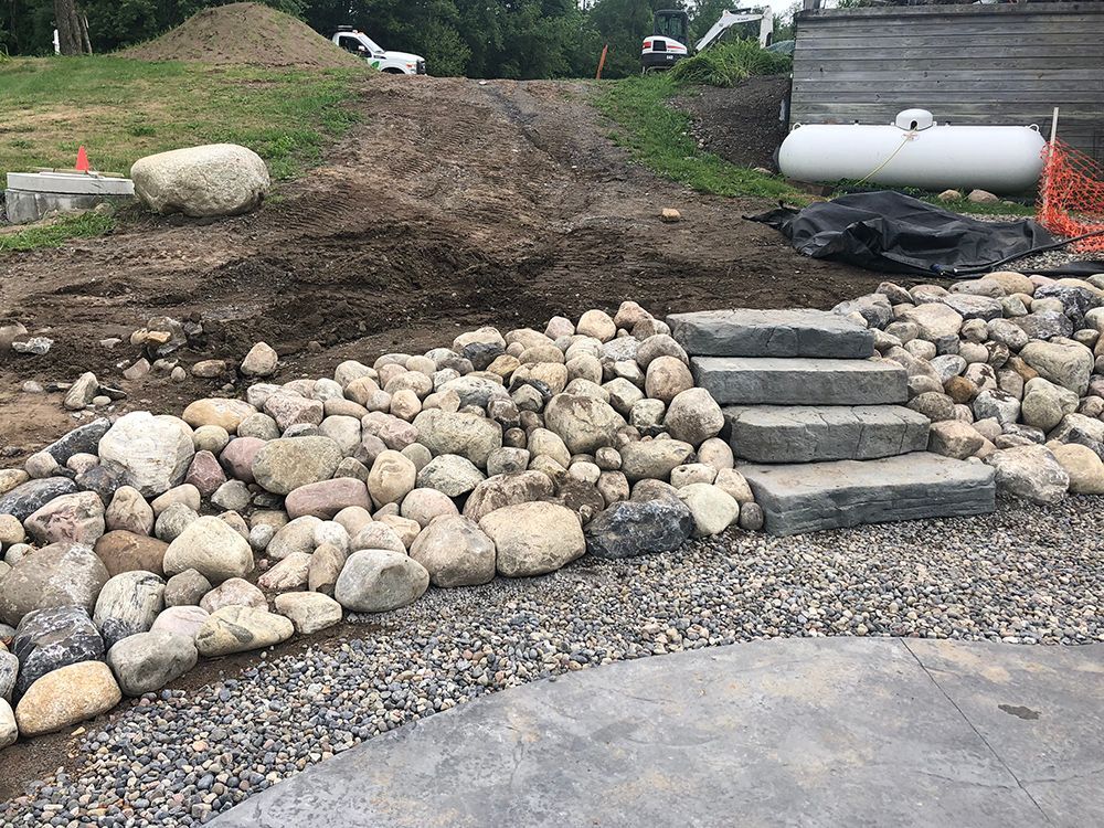 A pile of rocks and stairs are sitting on top of a gravel road.