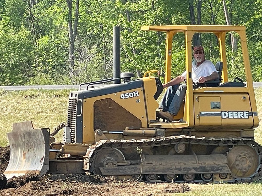 A man is driving a yellow deere bulldozer