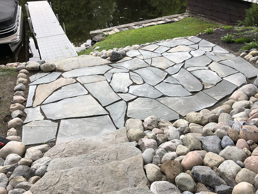 A stone walkway leading to a dock next to a body of water.