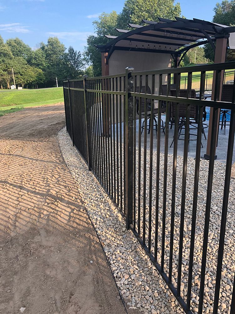 A metal fence surrounds a patio area with tables and chairs.