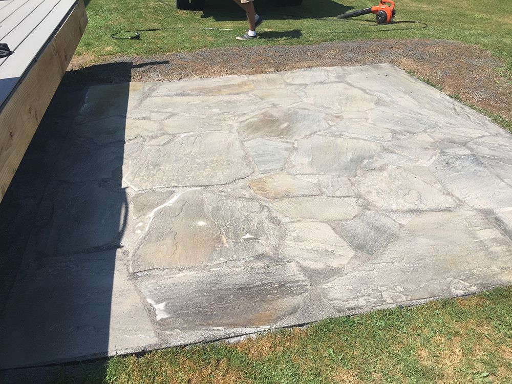 A man is standing on a stone patio next to a wooden deck.