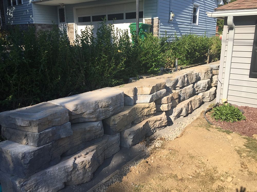 A stone wall is being built in front of a house.