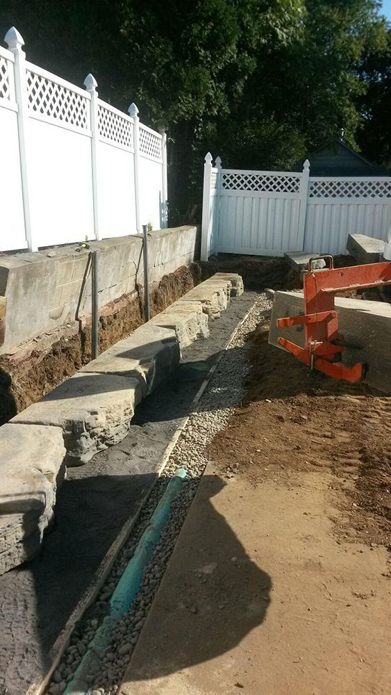 A white fence is surrounding a dirt area in a backyard.