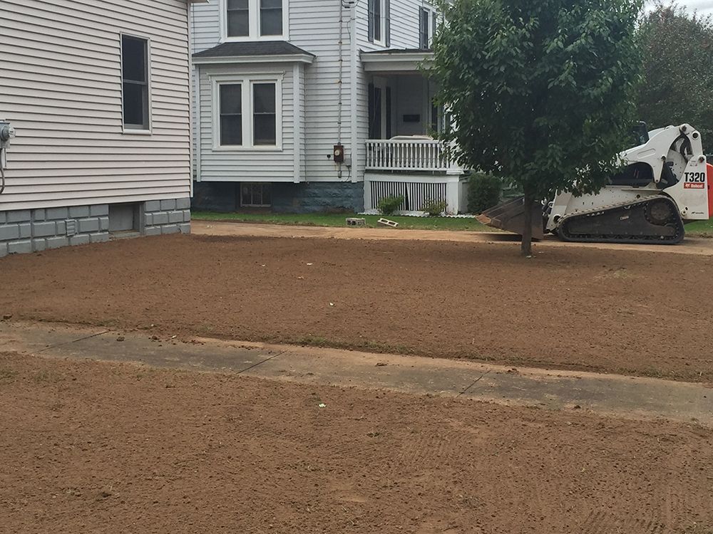 A bobcat is parked in front of a house
