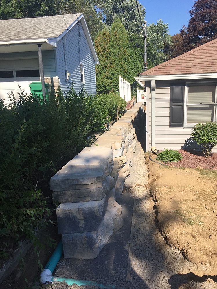 A stone wall is being built in front of a house