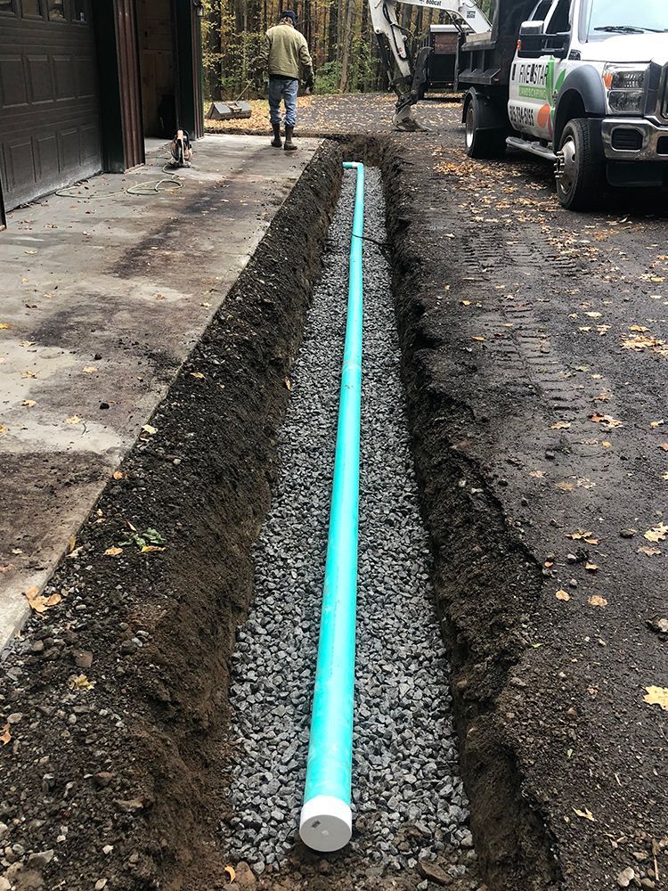 A green pipe is being installed in a trench next to a truck.