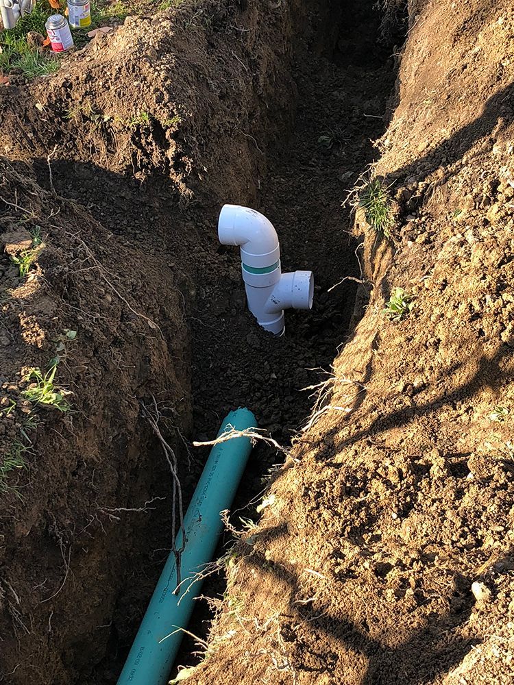 A drain pipe is being installed in a hole in the ground.