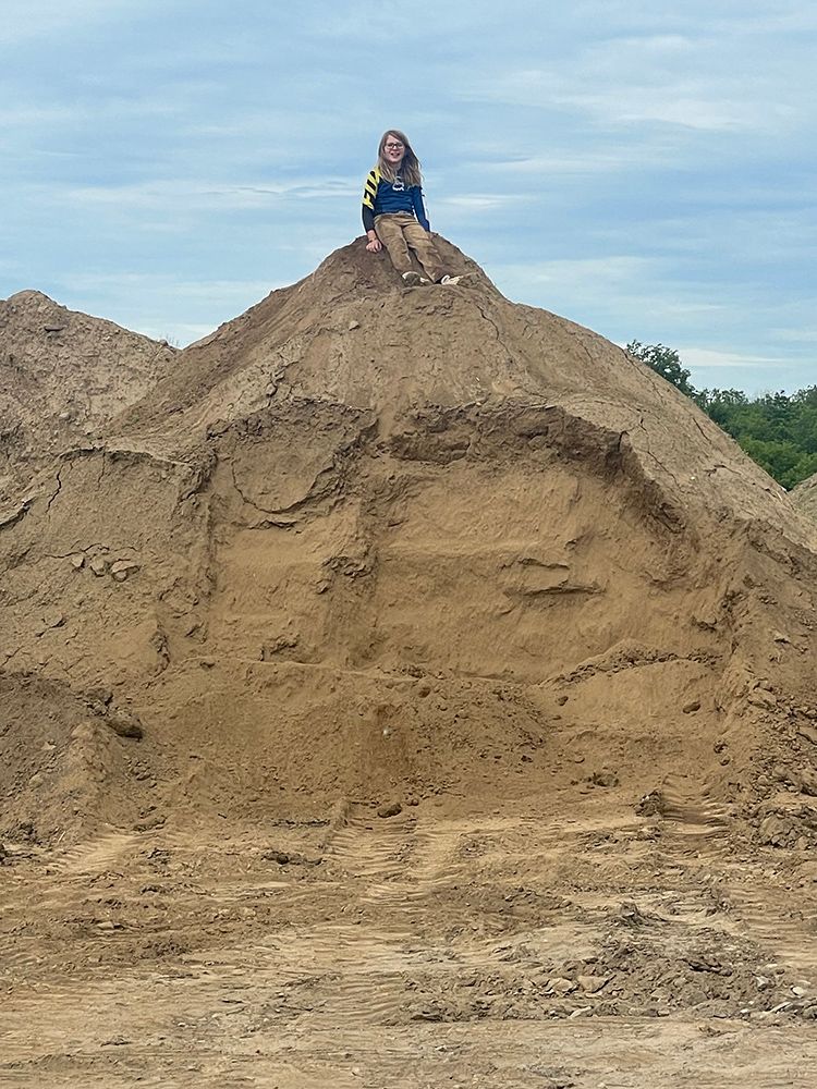 A little girl is sitting on top of a pile of dirt.