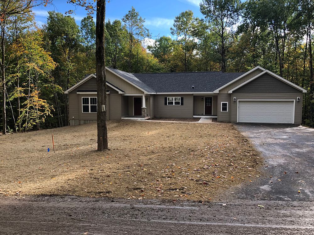 A house with a garage and a tree in front of it
