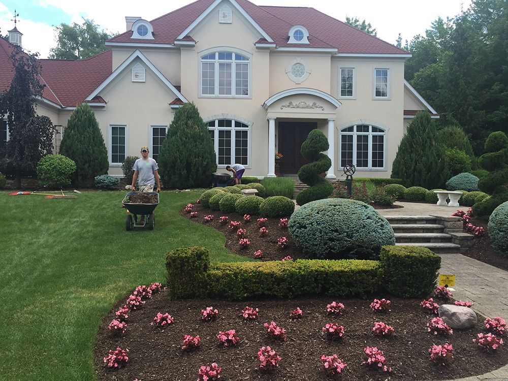 A man pushing a wheelbarrow in front of a large house
