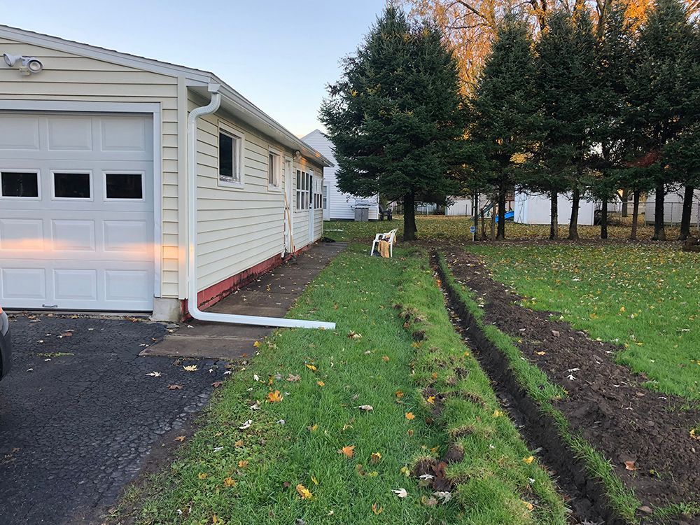 A house with a garage and a drain in front of it.