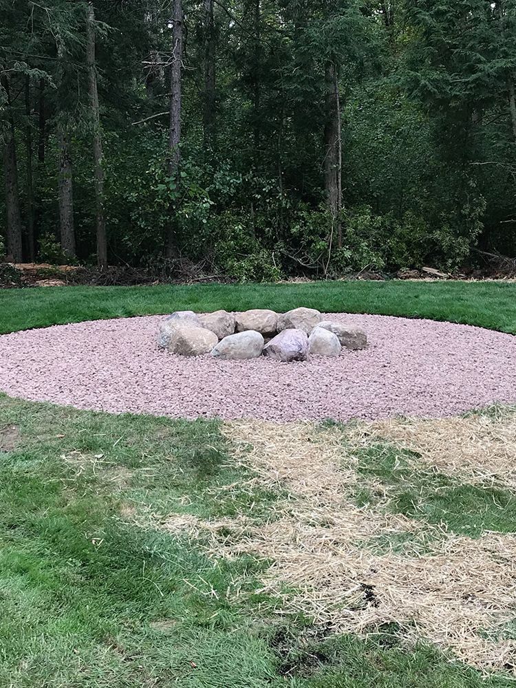 A fire pit is sitting in the middle of a lush green field.
