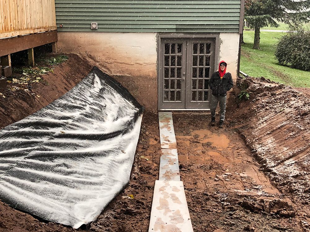 A man is standing in the dirt in front of a house.