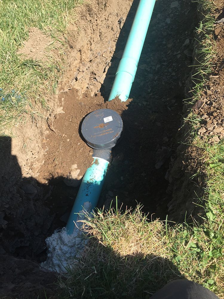 A green pipe is sitting in a hole in the ground.