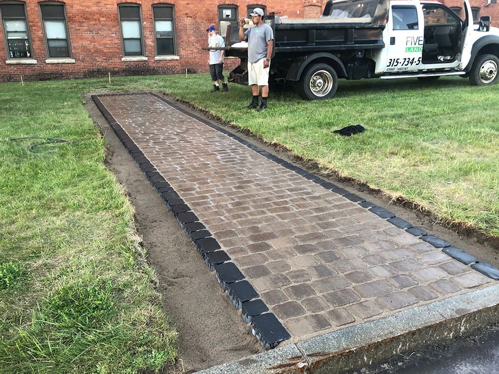 A man is standing next to a dump truck on a sidewalk.