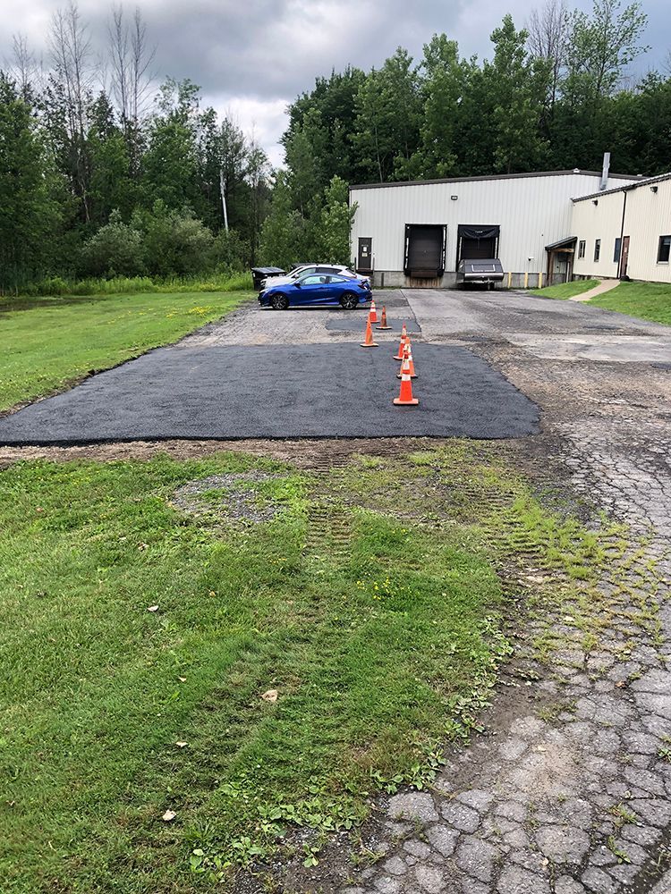 A blue car is parked in a parking lot next to a building.