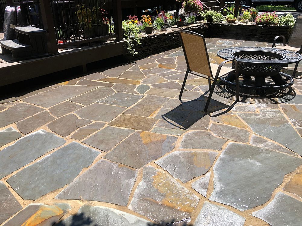 A stone patio with a fire pit and chairs