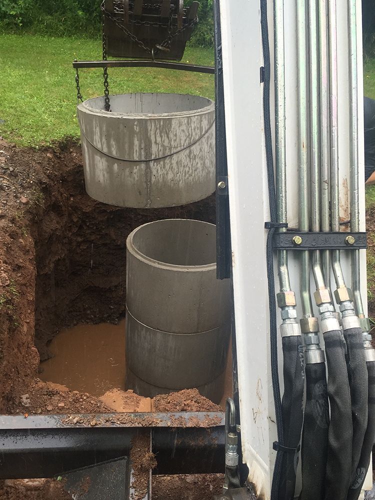 Two concrete rings are being installed in a hole in the ground.