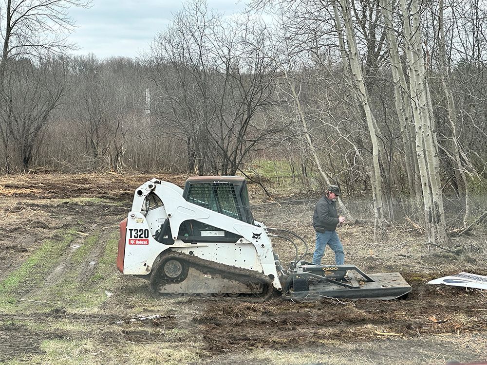 A man is standing next to a bulldozer in a field.