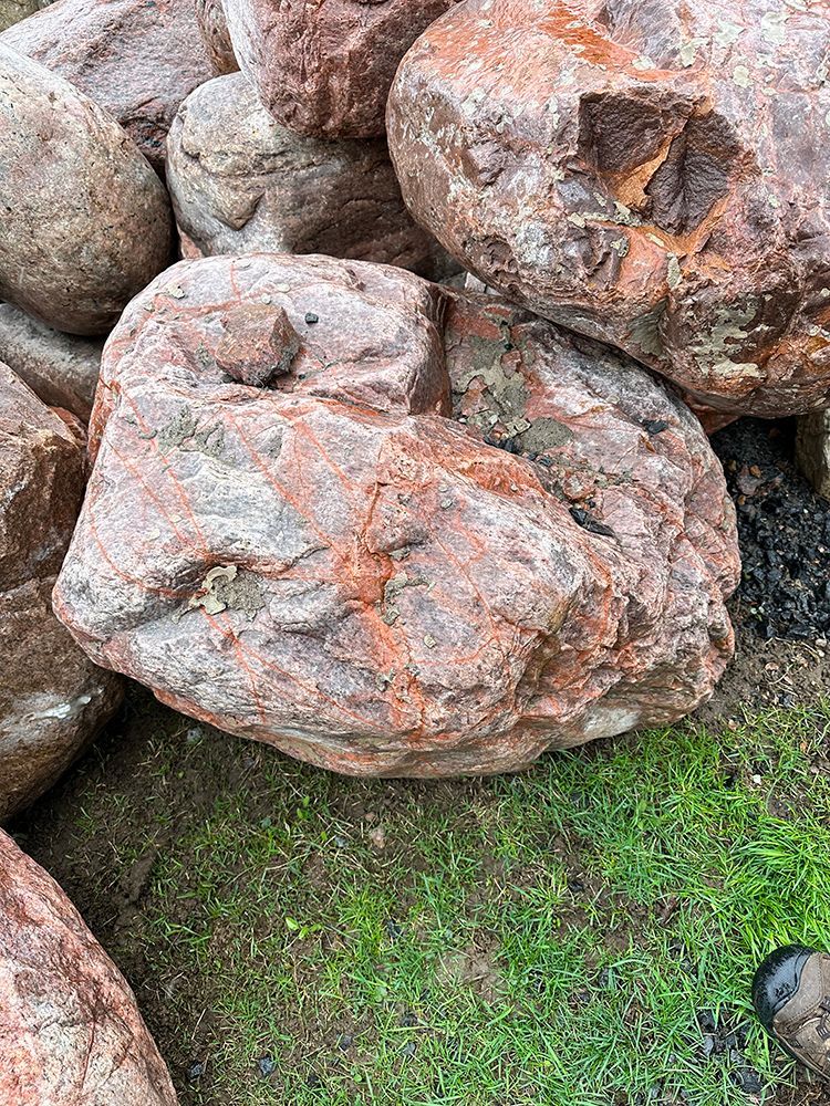 A pile of rocks sitting on top of a lush green field.
