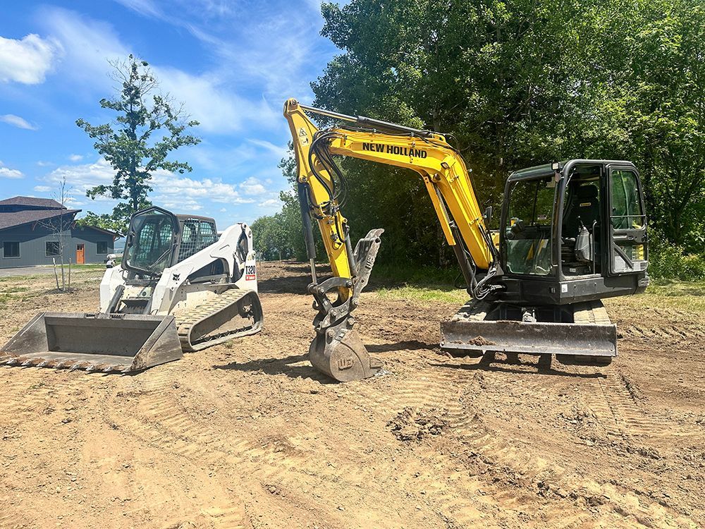 Two excavators are parked next to each other in a dirt field.