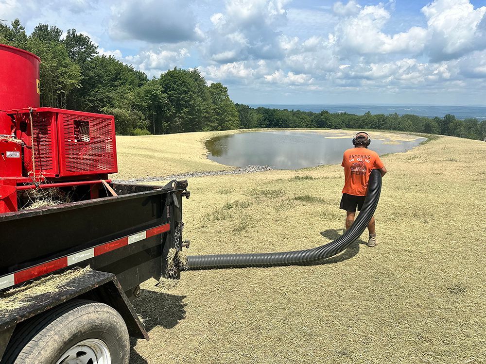 A man is standing next to a truck with a hose attached to it.