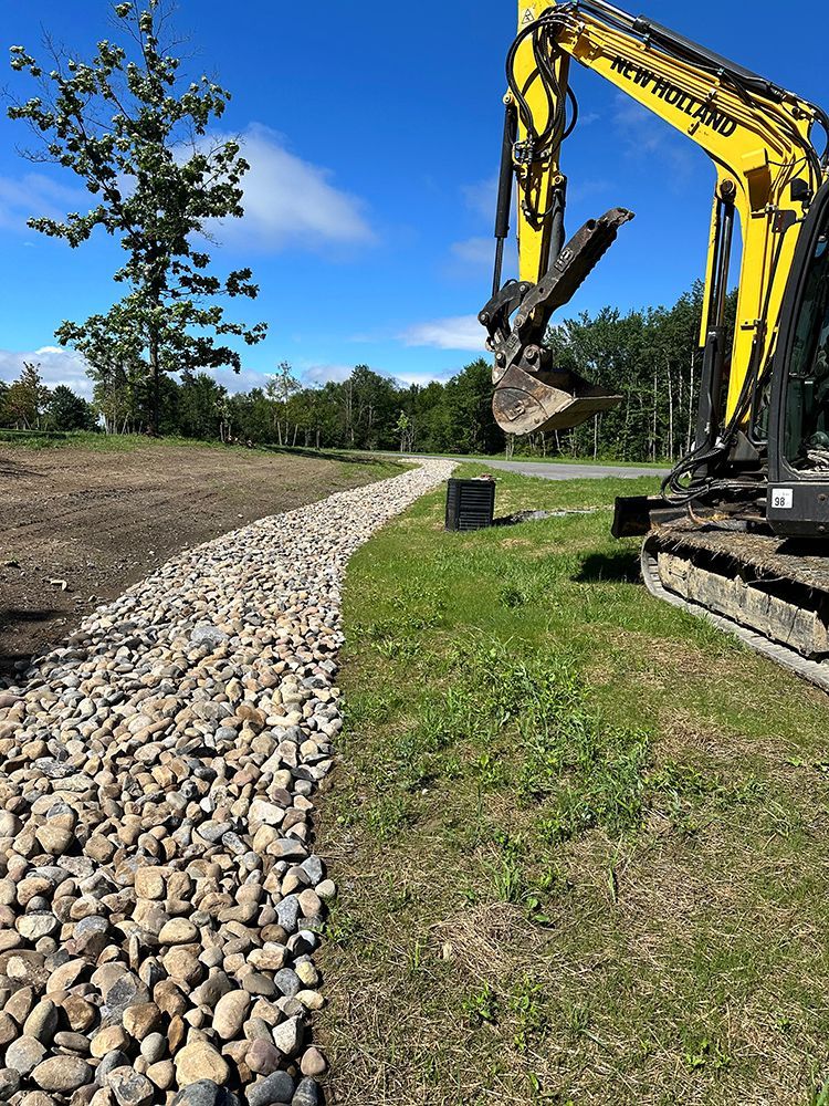 A yellow excavator is digging a path in the grass.
