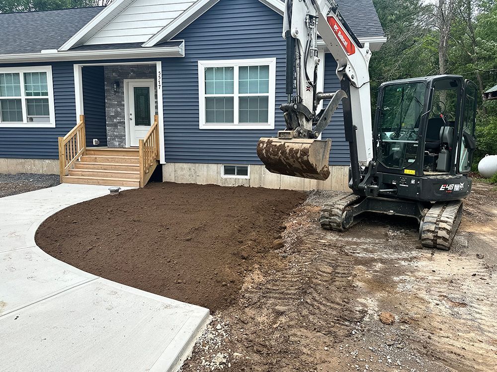A small excavator is digging dirt in front of a house.